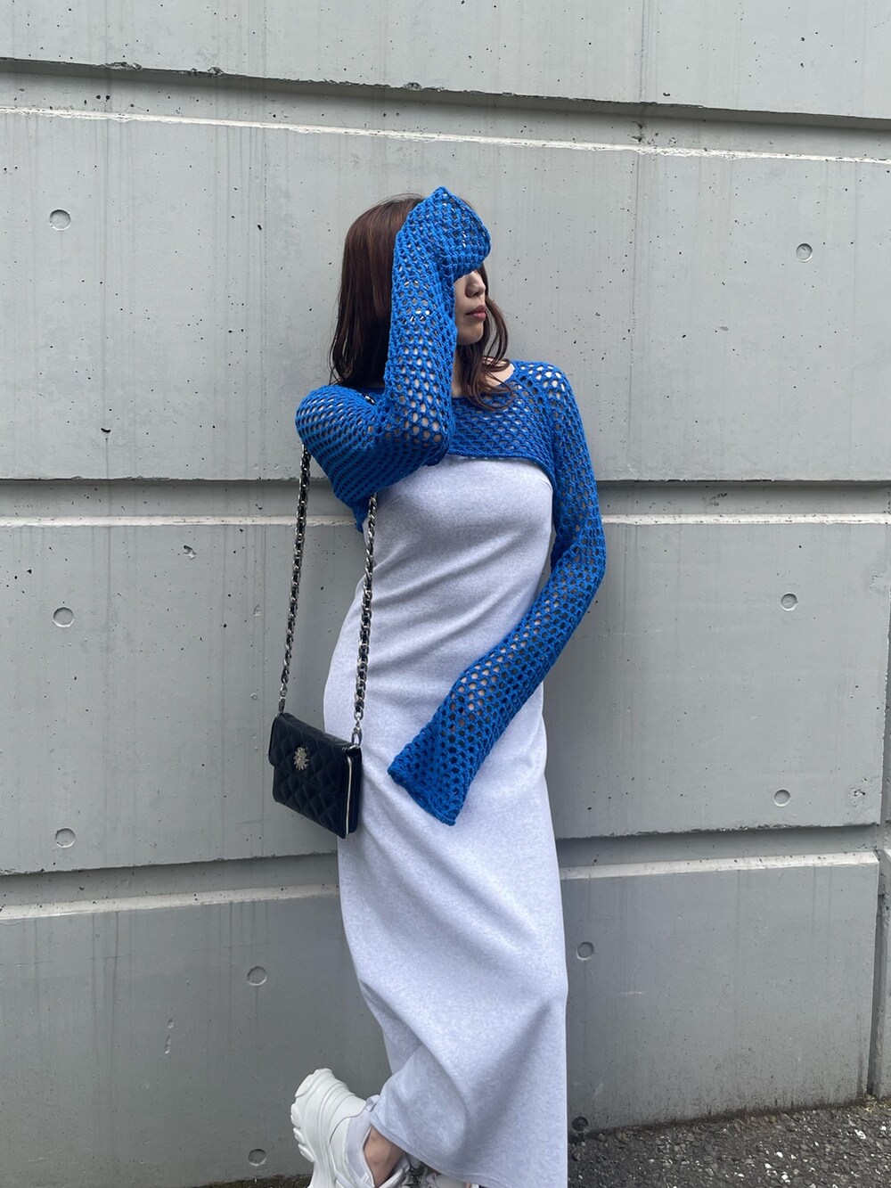 ブルー系のニット/セーター、ブラック系のショルダーバッグ、グレー系のワンピースを着用したレディースの春コーディネートの3枚目の写真