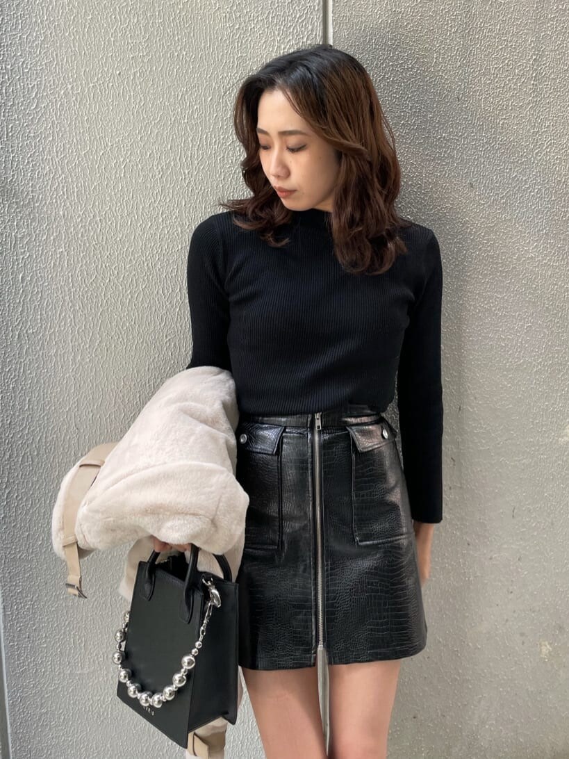 ブラック系のニット/セーター、ホワイト系のブルゾン、ブラック系のスカートを着用したレディースの秋コーディネートの4枚目の写真