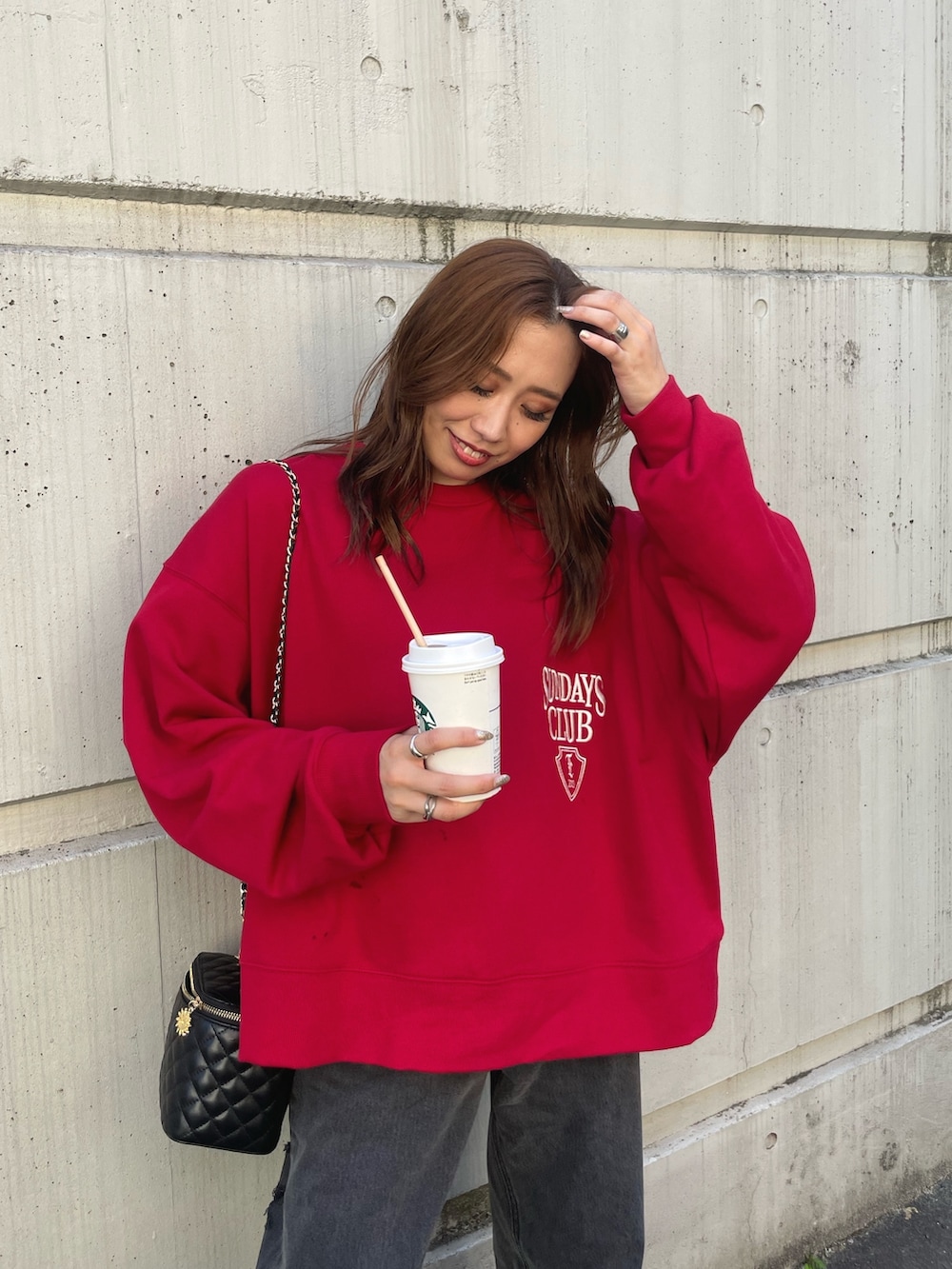 レッド系のスウェット、ブラック系のデニムパンツを着用したレディースの夏コーディネートの4枚目の写真