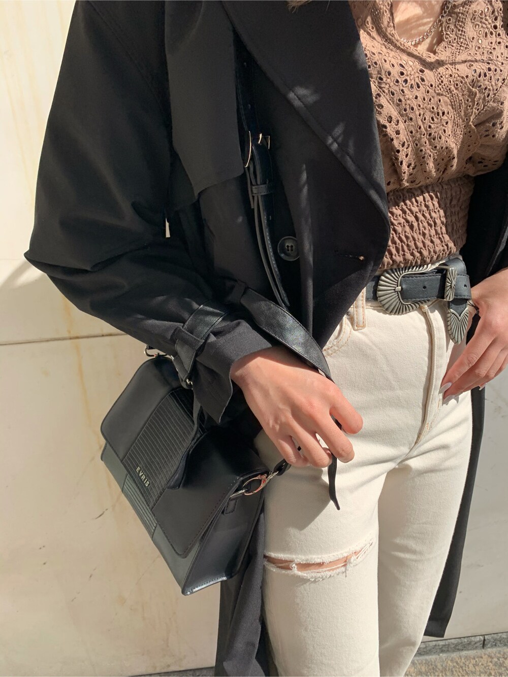 ブラック系のショルダーバッグ、ブラック系のトレンチコート、ホワイト系のデニムパンツを着用したレディースの冬コーディネートの8枚目の写真