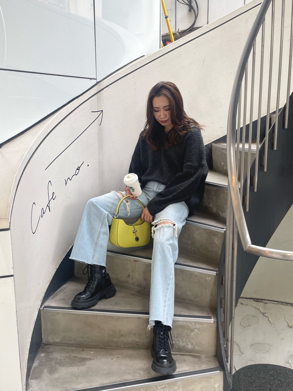 グレー系のニット/セーター、イエロー系のハンドバッグ、ブルー系のデニムパンツを着用したレディースの秋コーディネートの3枚目の写真