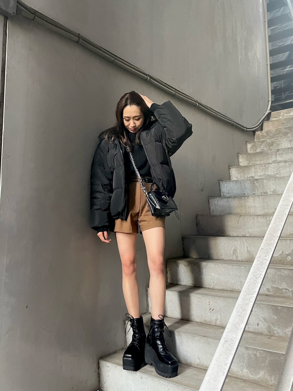 ブラウン系のその他パンツ、ブラック系のハンドバッグ、ブラック系のダウンジャケット/コートを着用したレディースの秋コーディネートの2枚目の写真