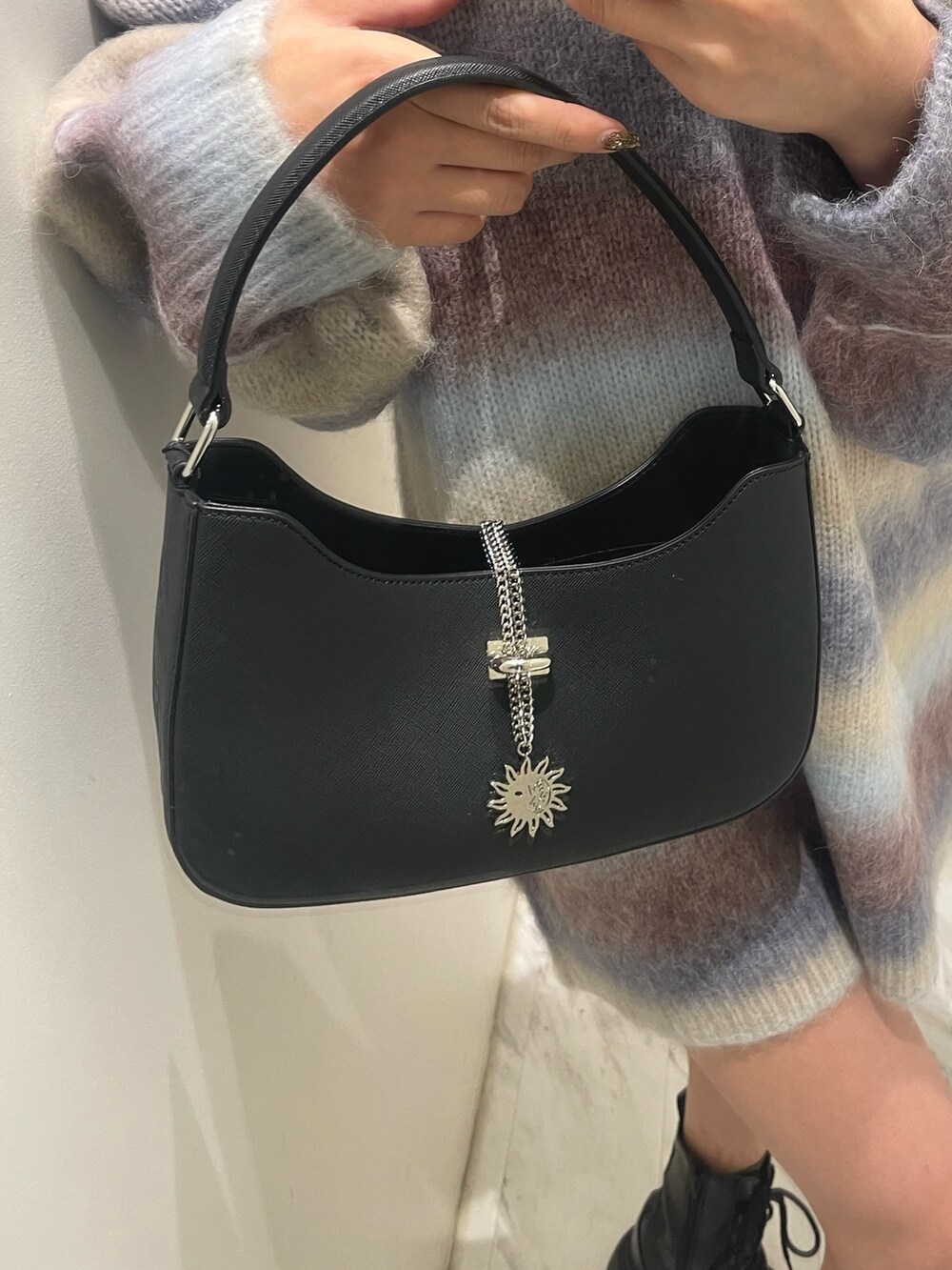 パープル系のニット/セーター、ブラック系のハンドバッグ、ブラック系のブーツを着用したレディースの秋コーディネートの4枚目の写真