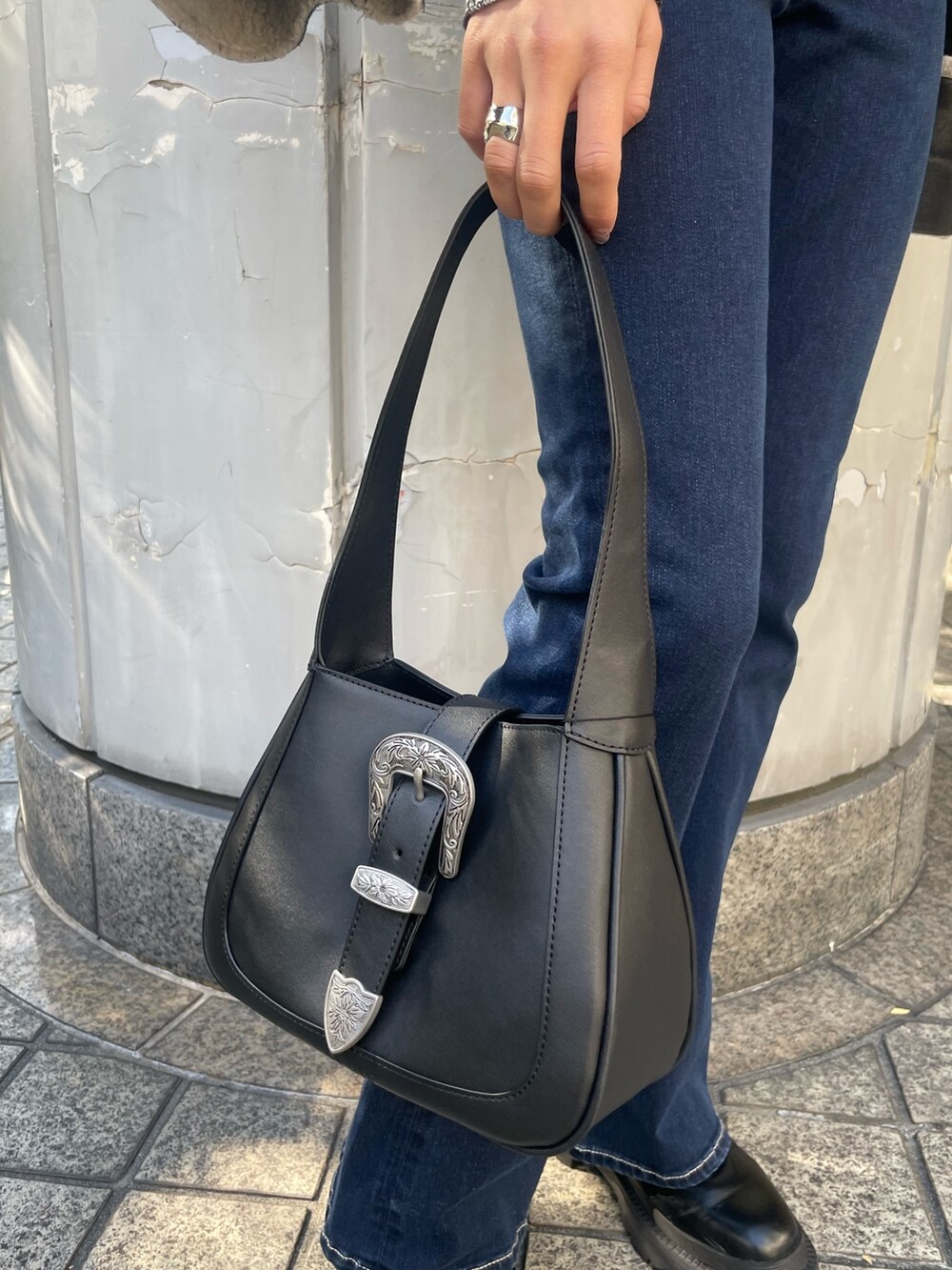 ブラック系のブルゾン、ブラック系のニット/セーター、ブルー系のデニムパンツを着用したレディースの冬コーディネートの7枚目の写真