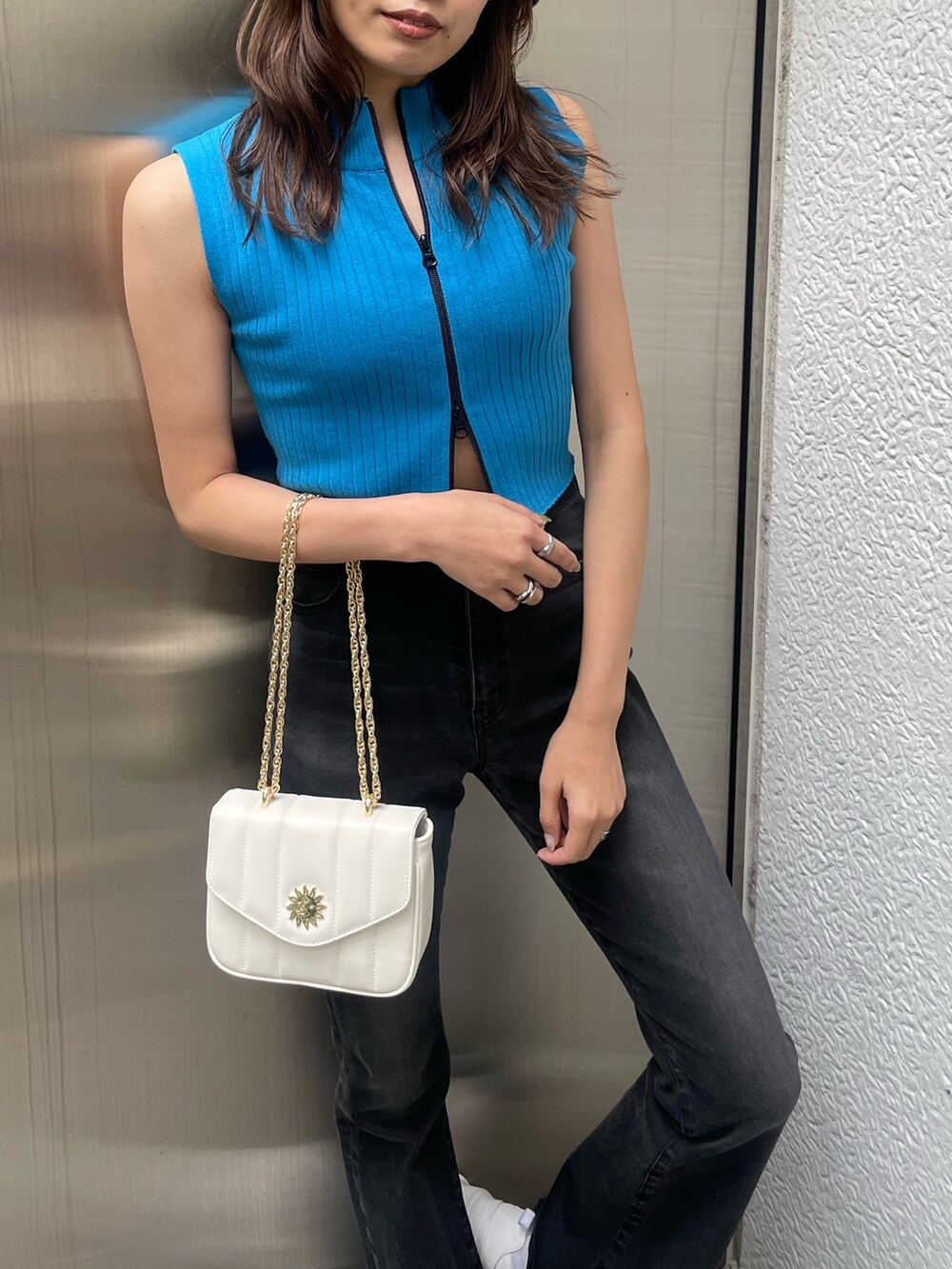 ブルー系のタンクトップ、ブラック系のデニムパンツ、ホワイト系のスニーカーを着用したレディースの春コーディネートの4枚目の写真