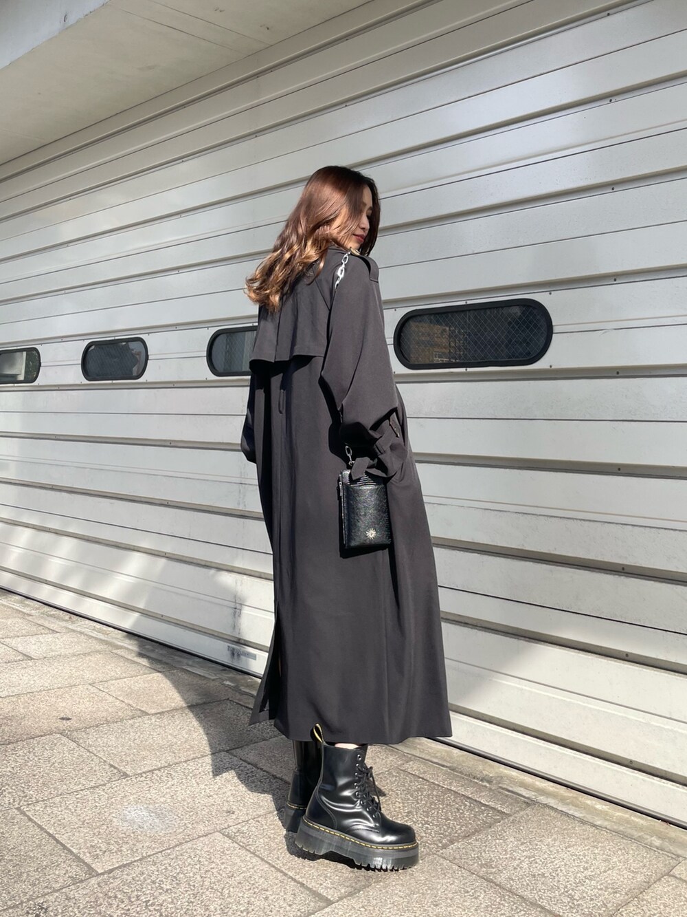 ブラック系のショルダーバッグ、ブラック系のトレンチコート、ホワイト系のワンピースを着用したレディースの冬コーディネートの3枚目の写真