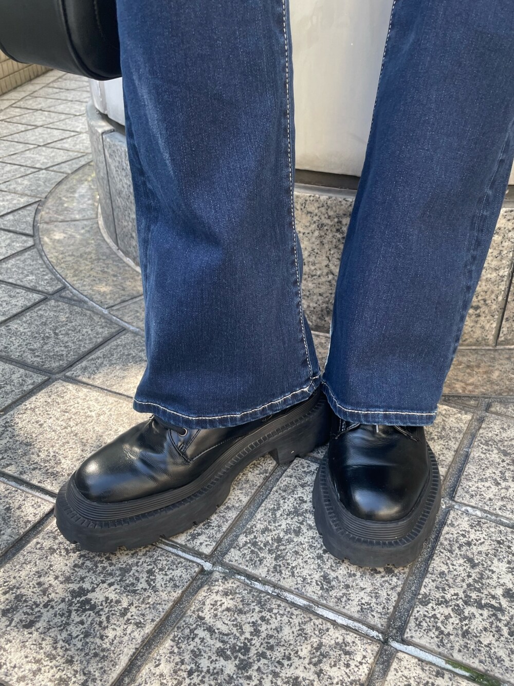 ブラック系のブルゾン、ブラック系のニット/セーター、ブルー系のデニムパンツを着用したレディースの冬コーディネートの10枚目の写真