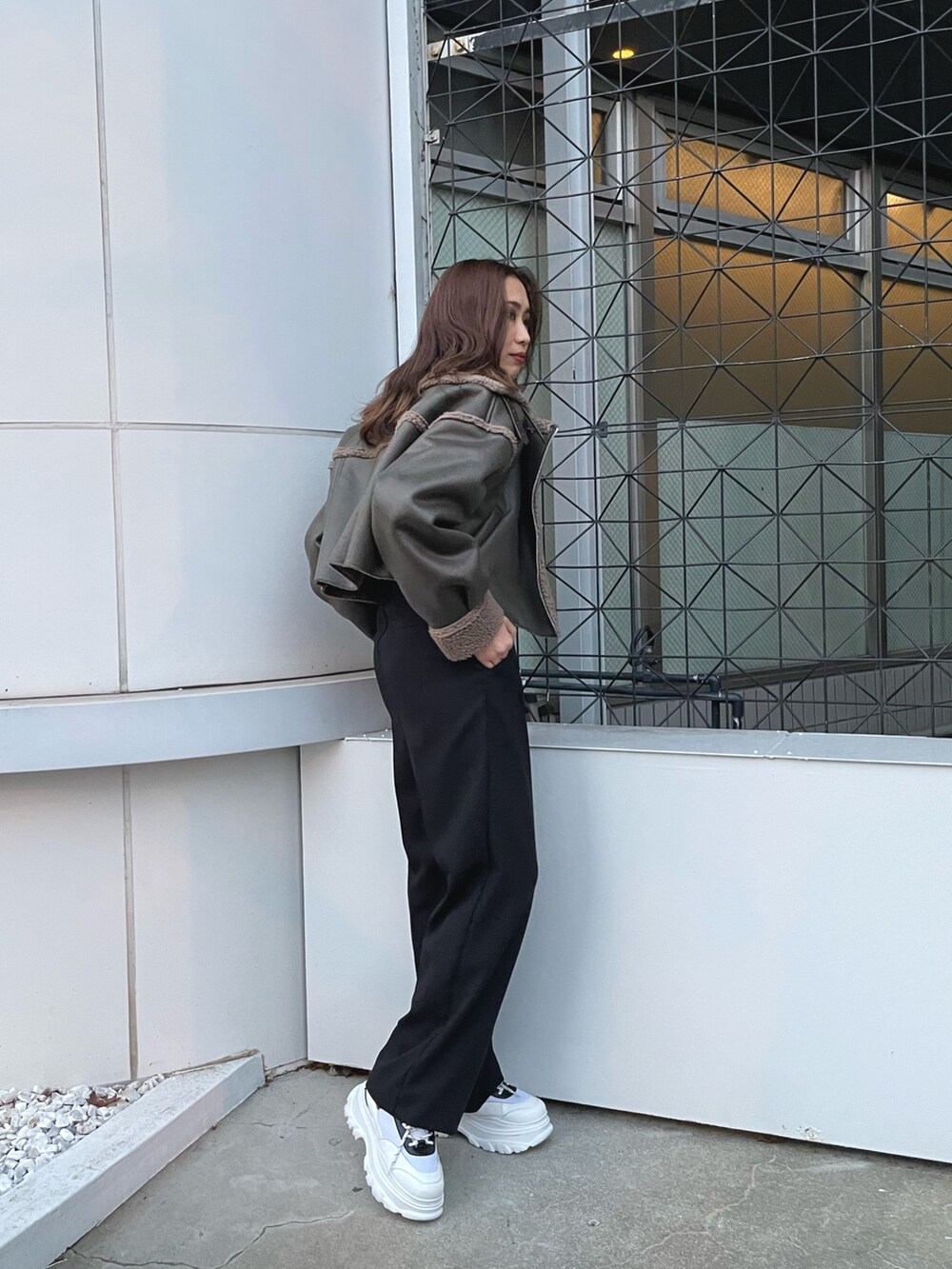 グリーン系のブルゾン、ホワイト系のスウェット、ブラック系のスラックスを着用したレディースの冬コーディネートの2枚目の写真