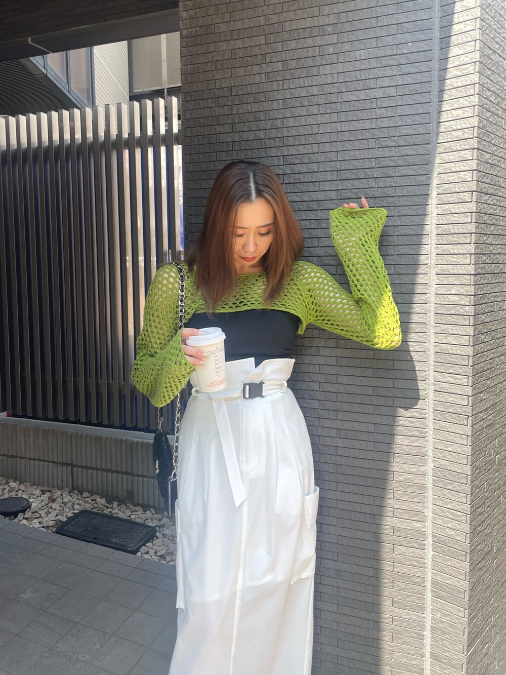 グリーン系のニット/セーター、ブラック系のニット/セーター、ホワイト系のスカートを着用したレディースの春コーディネートの3枚目の写真