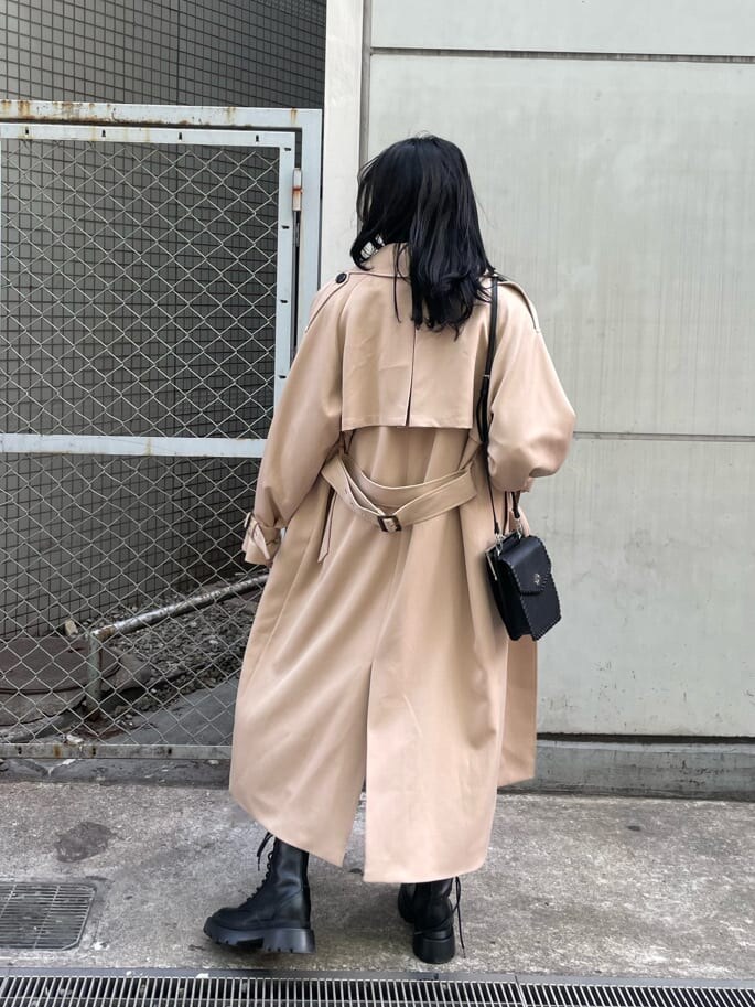 ベージュ系のスカート、ブラック系のブーツ、ベージュ系のトレンチコートを着用したレディースの春コーディネートの2枚目の写真