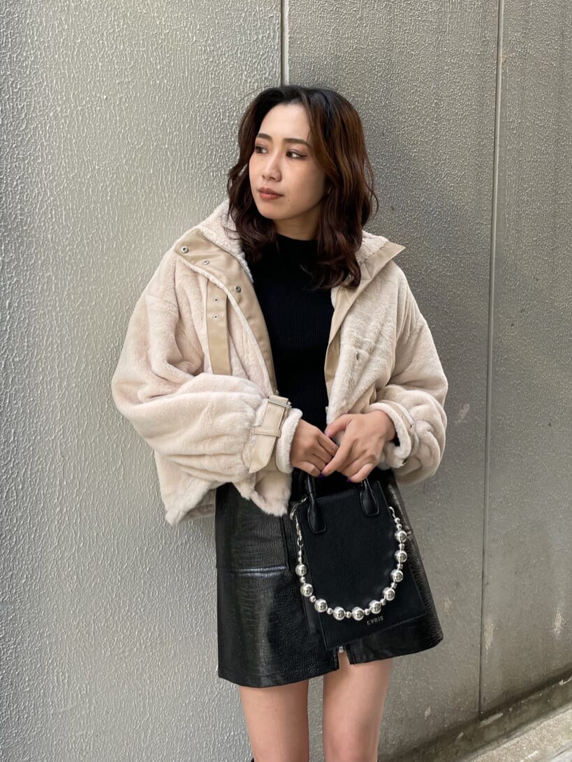 ブラック系のニット/セーター、ホワイト系のブルゾン、ブラック系のスカートを着用したレディースの秋コーディネートの3枚目の写真