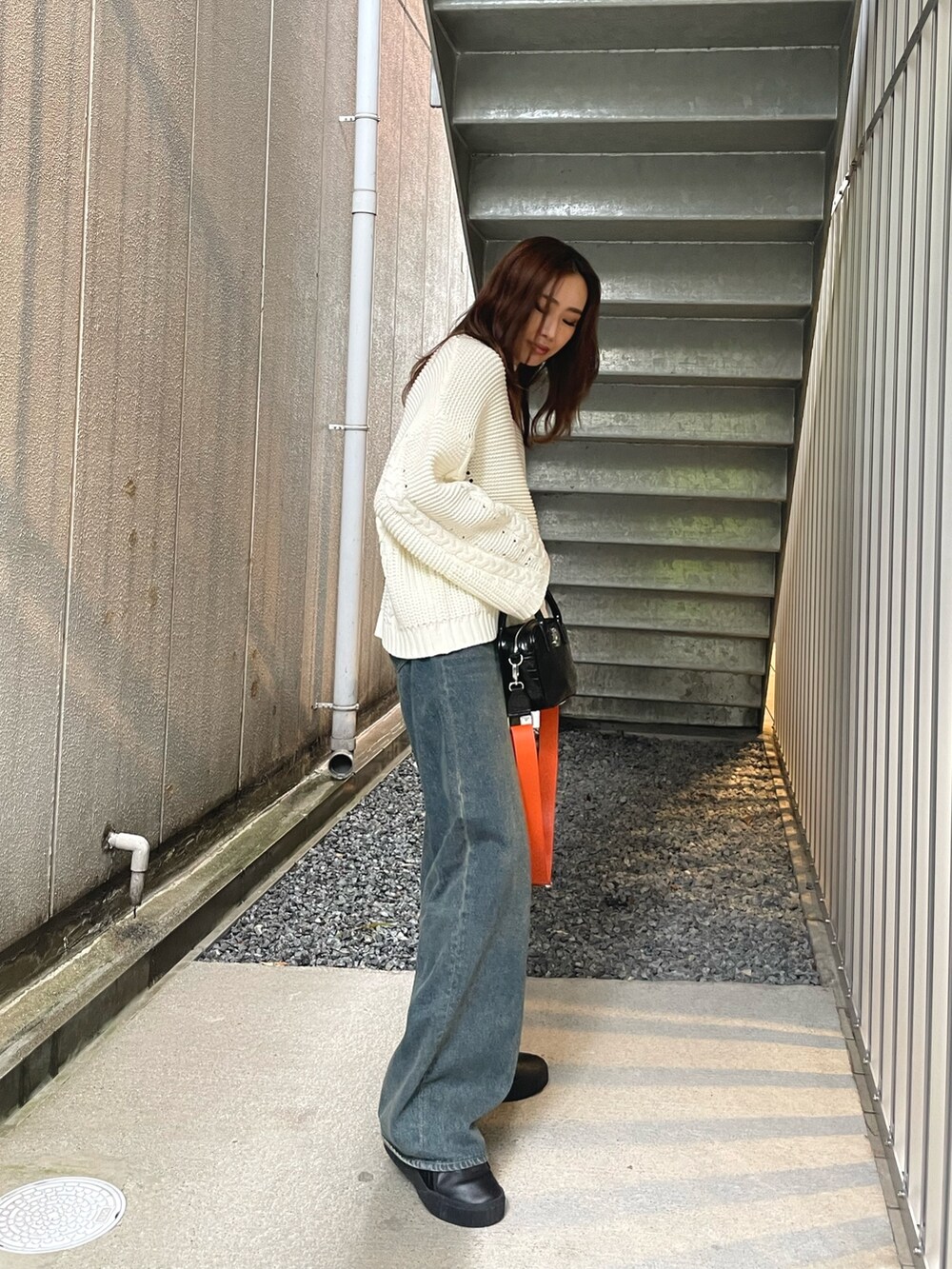 ホワイト系のニット/セーター、ブルー系のデニムパンツ、ホワイト系のショルダーバッグを着用したレディースの冬コーディネートの6枚目の写真