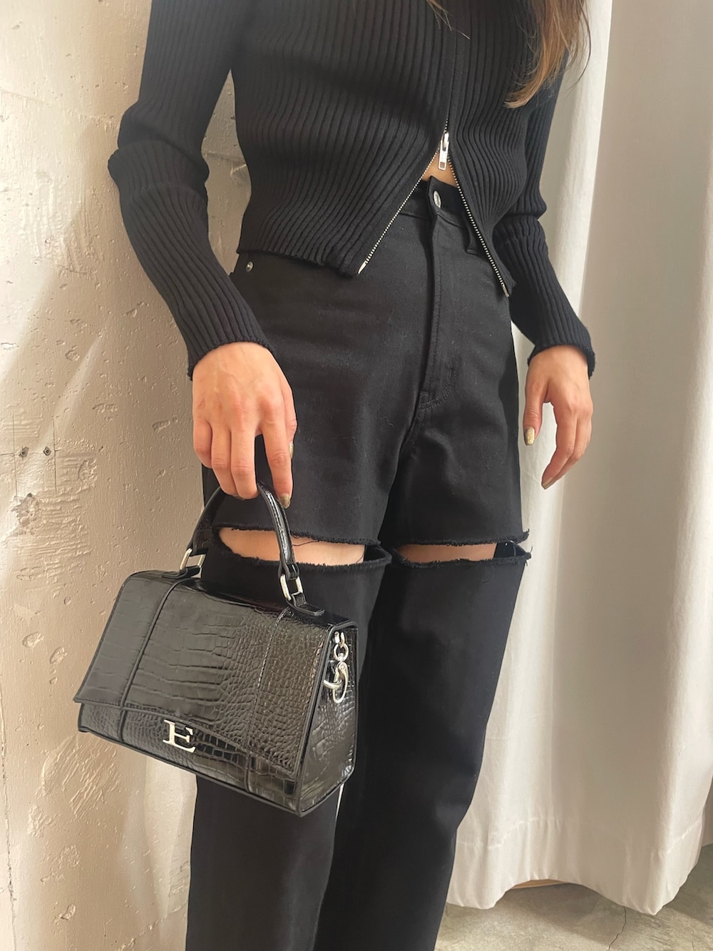 ブラック系のニット/セーター、ブラック系のショルダーバッグ、ホワイト系のブーツを着用したレディースの秋コーディネートの6枚目の写真