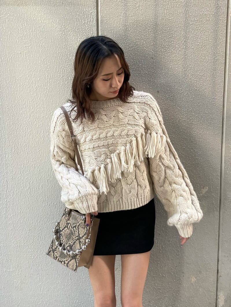 ベージュ系のブーツ、ホワイト系のニット/セーター、ブラック系のスカートを着用したレディースの秋コーディネートの3枚目の写真