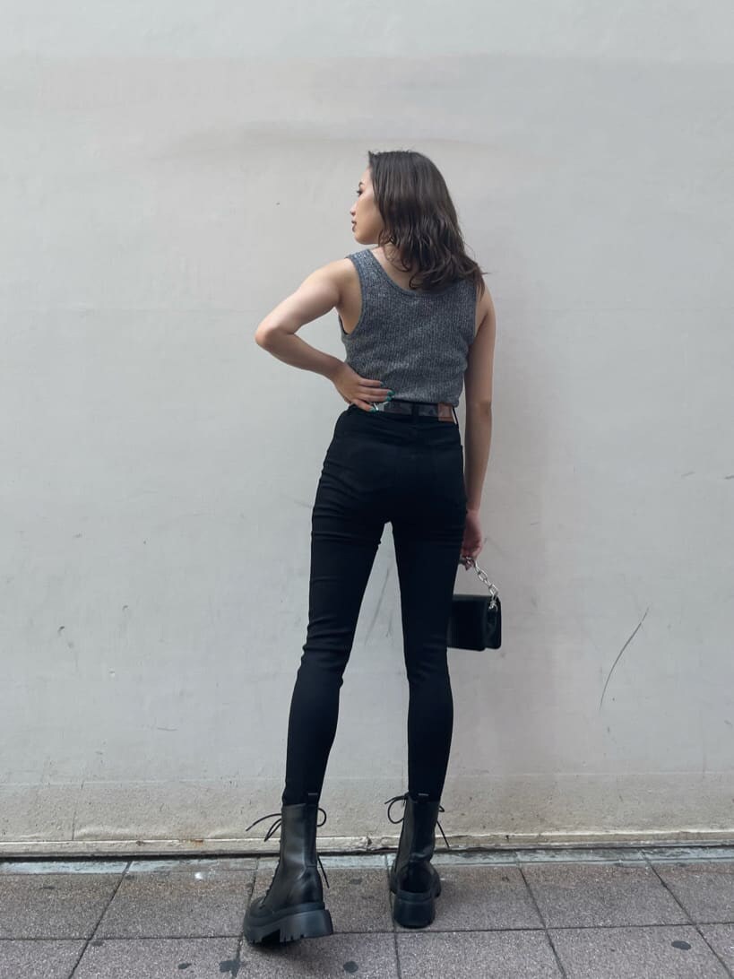 ブラック系のニット/セーター、ブラック系のブーツ、ブラック系のデニムパンツを着用したレディースの夏コーディネートの2枚目の写真