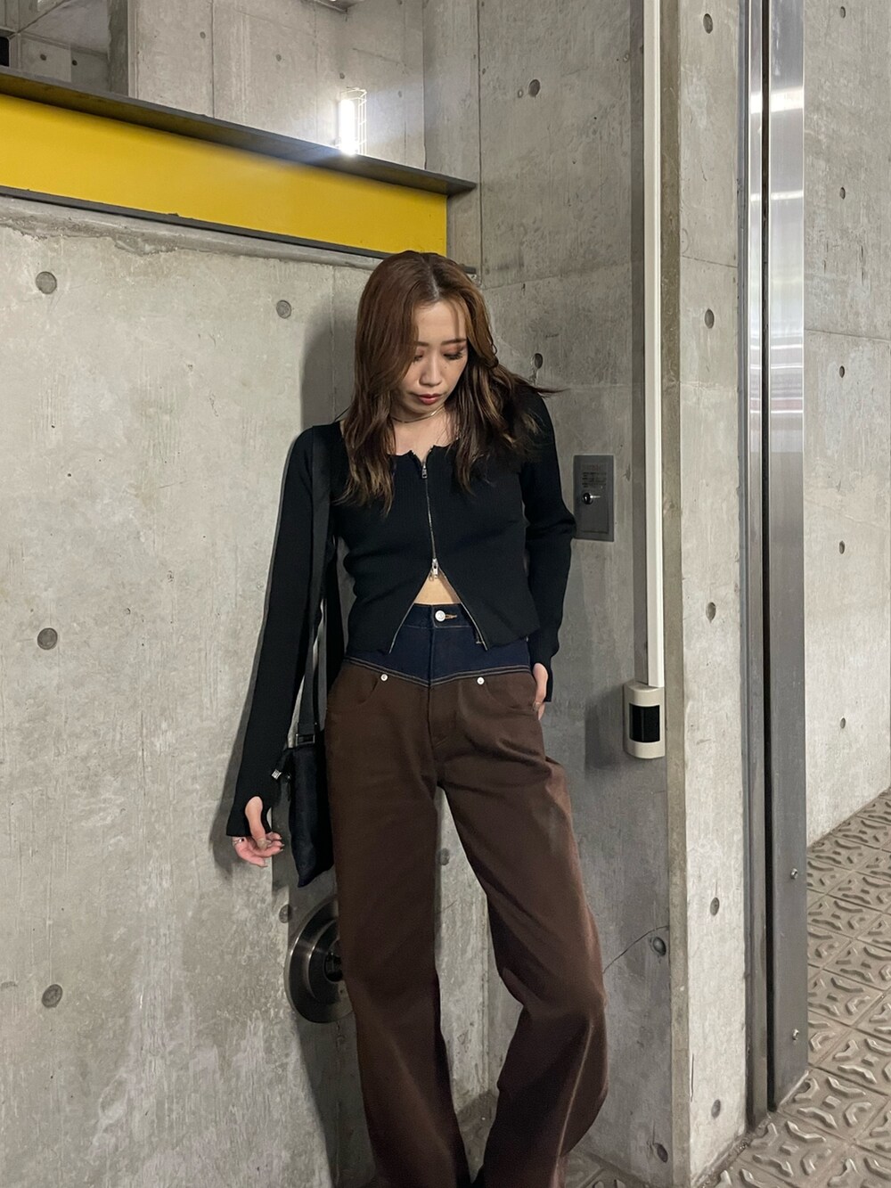 ブラウン系のデニムパンツ、ブラック系のニット/セーター、ブラック系のブーツを着用したレディースの夏コーディネートの3枚目の写真