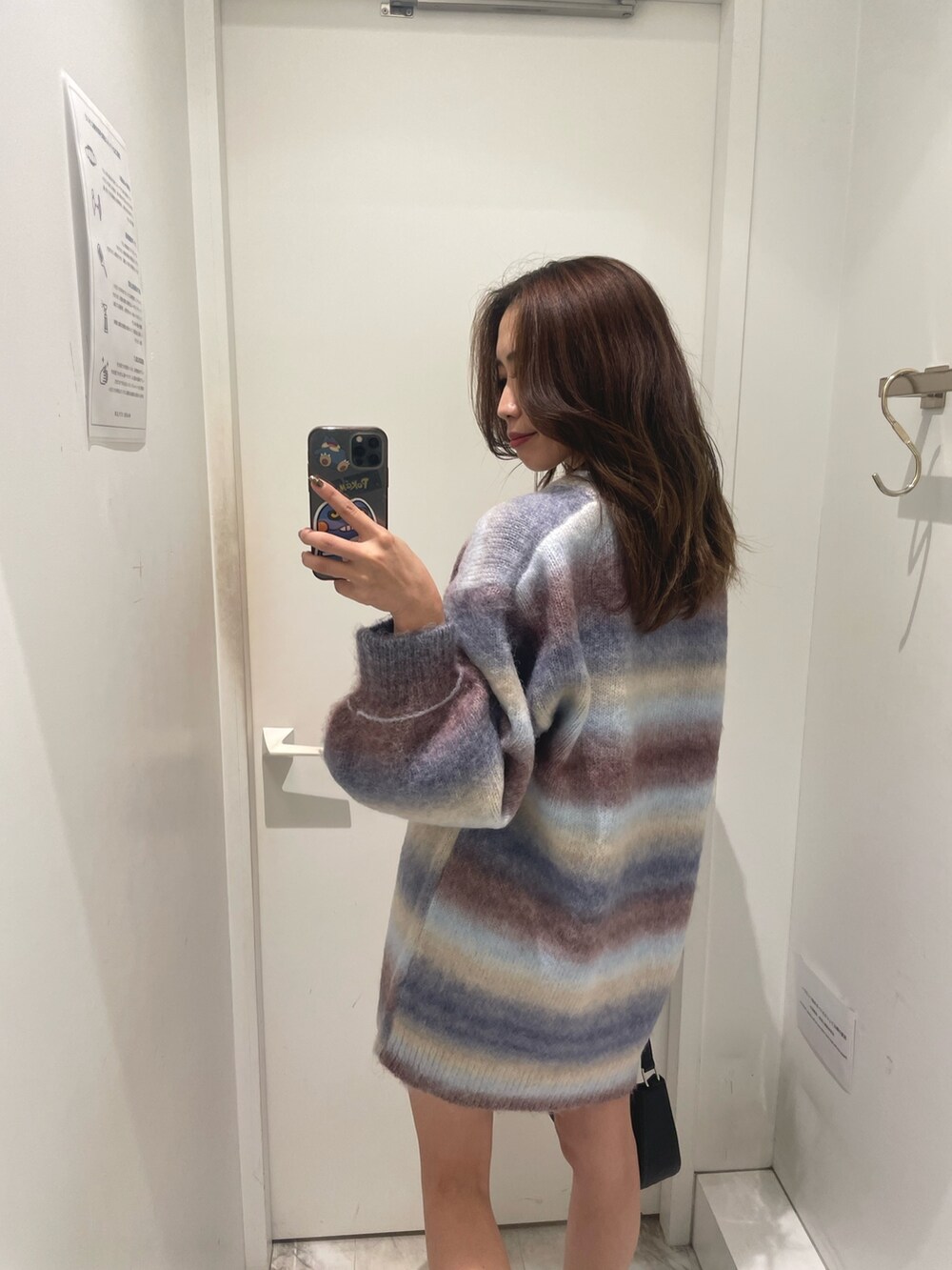 パープル系のニット/セーター、ブラック系のハンドバッグ、ブラック系のブーツを着用したレディースの秋コーディネートの3枚目の写真