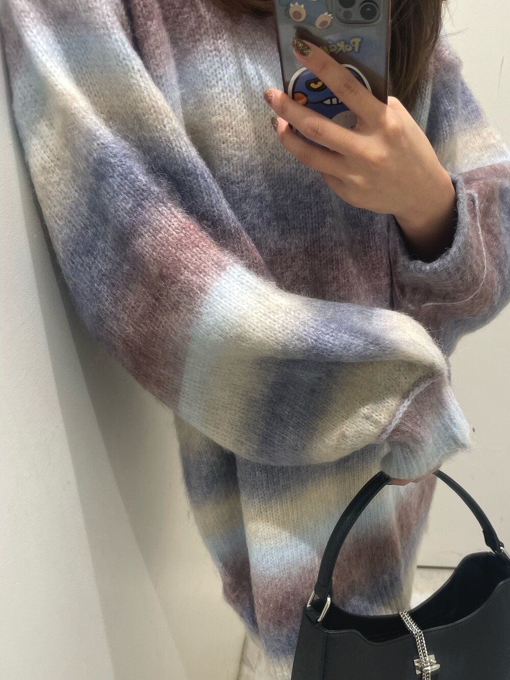 パープル系のニット/セーター、ブラック系のハンドバッグ、ブラック系のブーツを着用したレディースの秋コーディネートの5枚目の写真