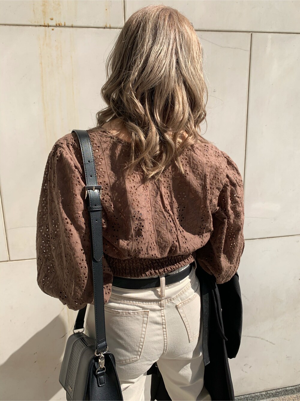 ブラック系のショルダーバッグ、ブラック系のトレンチコート、ホワイト系のデニムパンツを着用したレディースの冬コーディネートの5枚目の写真