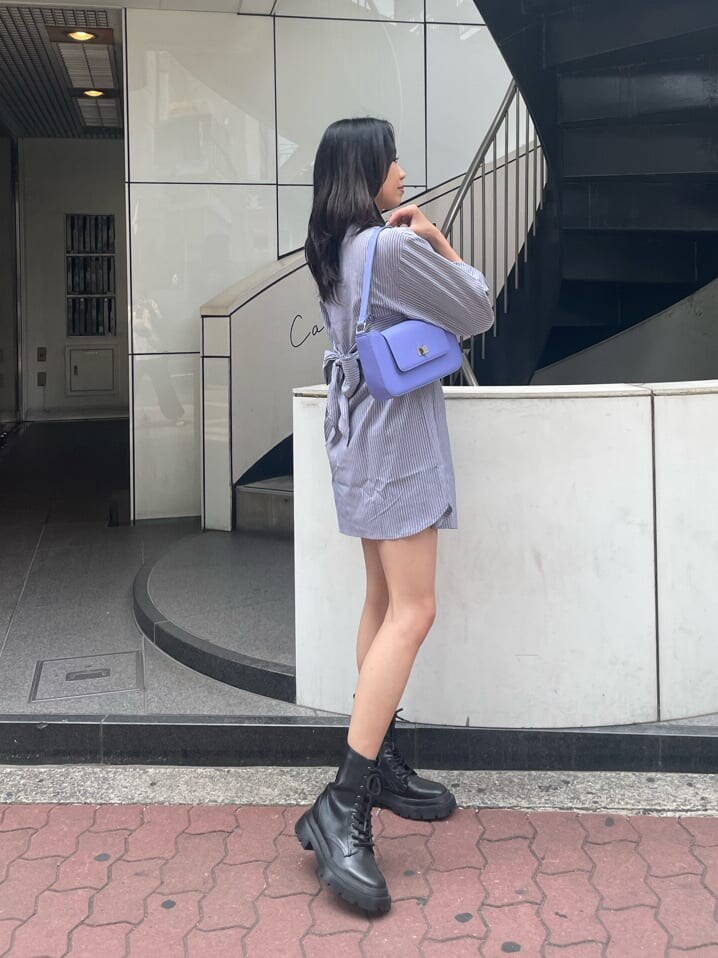 ブラック系のブーツ、ブラック系のワンピース、パープル系のショルダーバッグを着用したレディースの春コーディネートの5枚目の写真