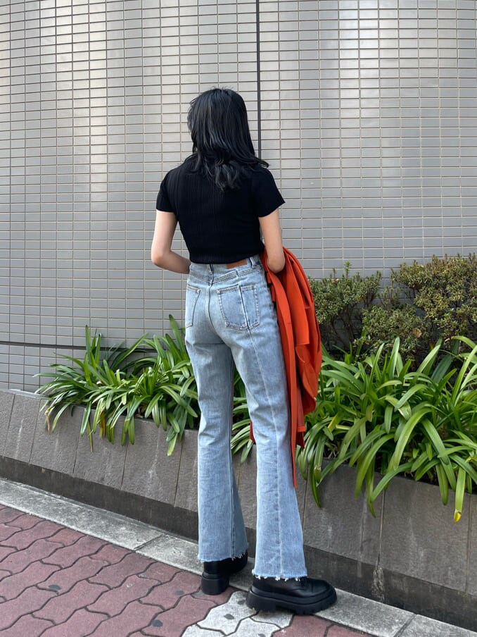 ブラック系のブーツ、オレンジ系のトレンチコート、ブルー系のデニムパンツを着用したレディースの春コーディネートの6枚目の写真