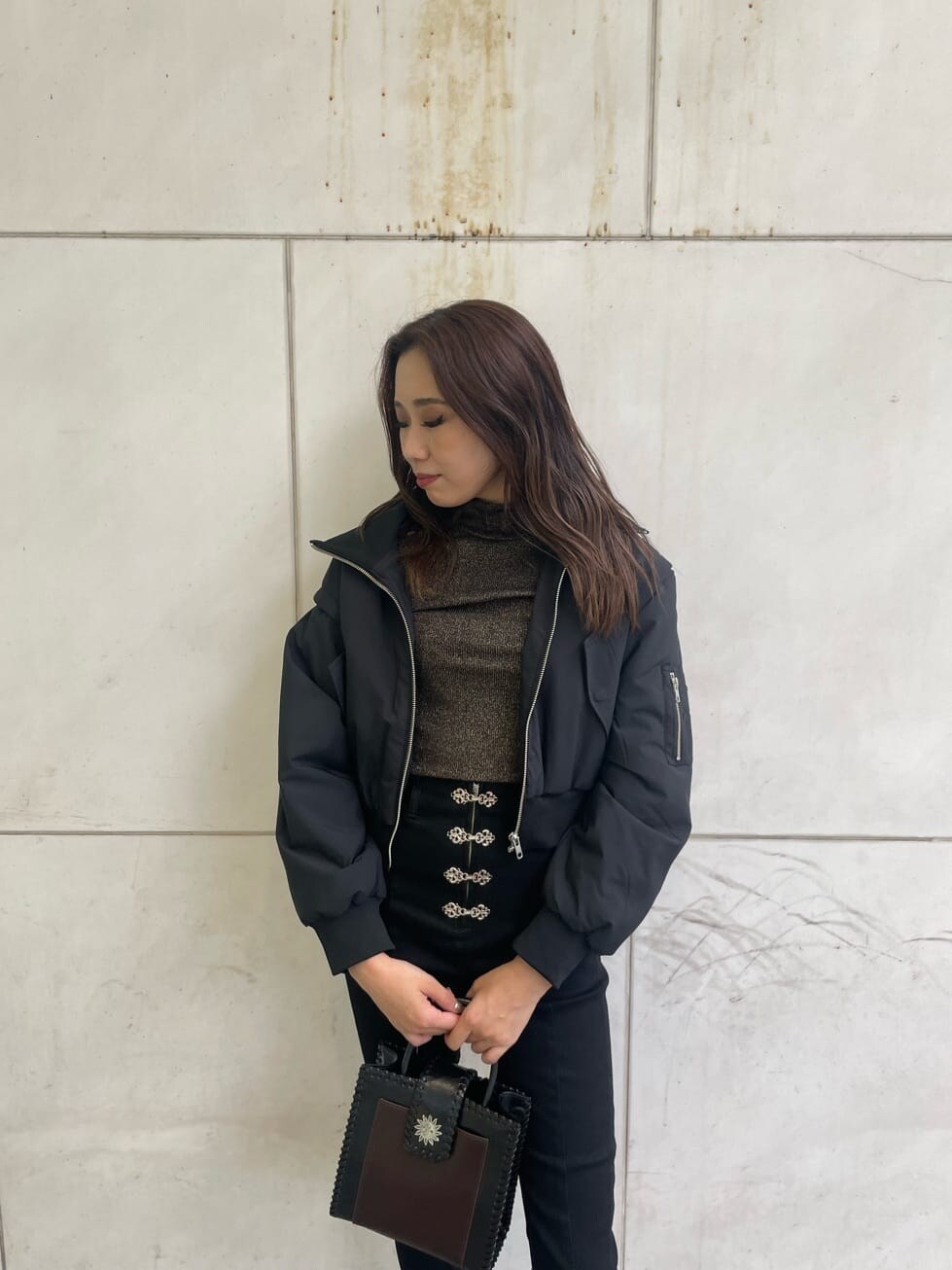 ブラック系のブーツ、ブラック系のデニムパンツ、ブラック系のショルダーバッグを着用したレディースの秋コーディネートの4枚目の写真