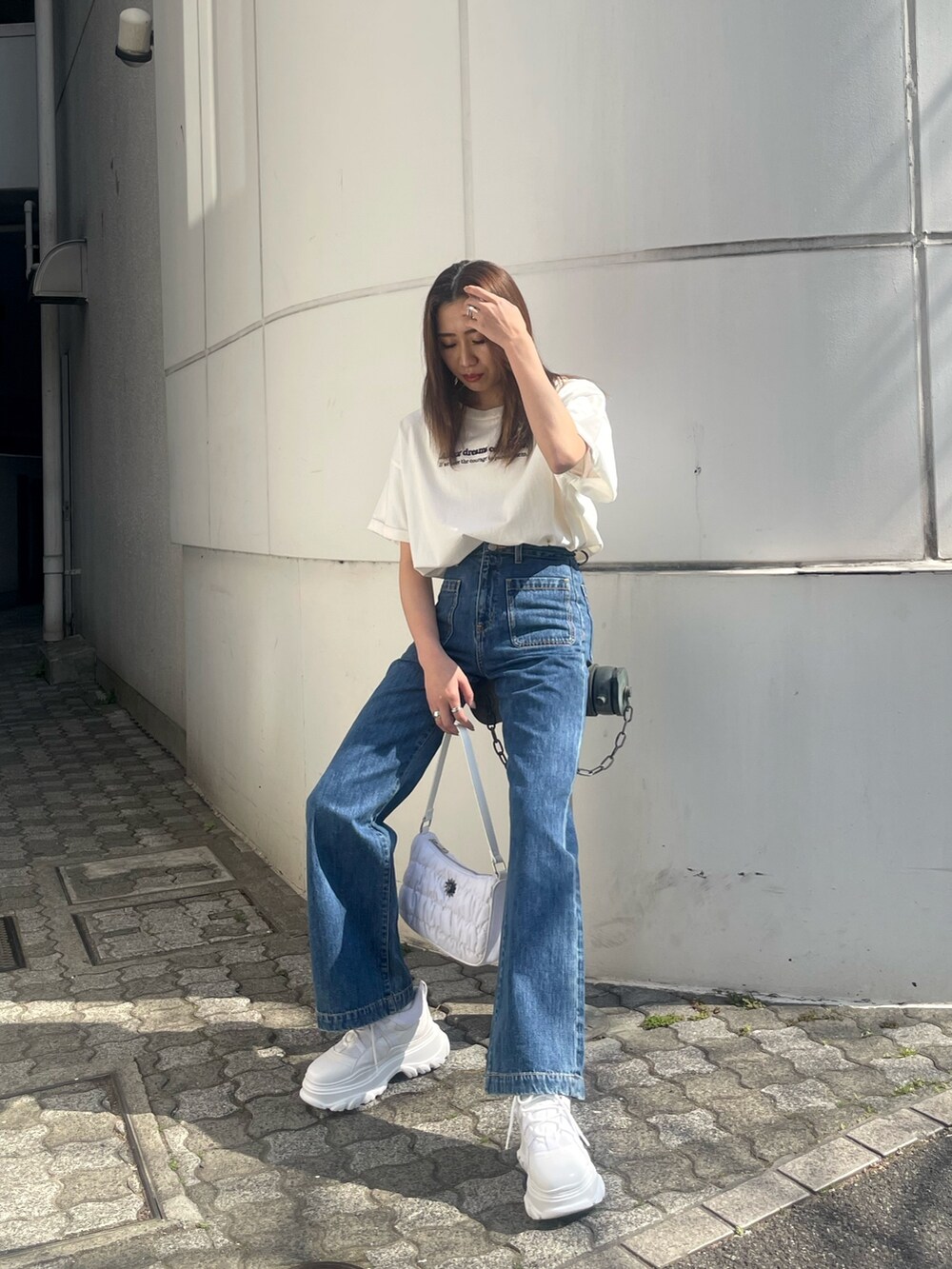 ホワイト系のTシャツ/カットソー、ブルー系のデニムパンツ、ホワイト系のハンドバッグを着用したレディースの春コーディネートの2枚目の写真
