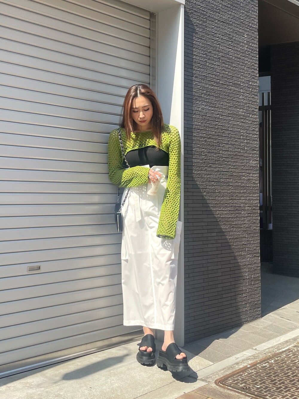 グリーン系のニット/セーター、ブラック系のニット/セーター、ホワイト系のスカートを着用したレディースの春コーディネートの5枚目の写真