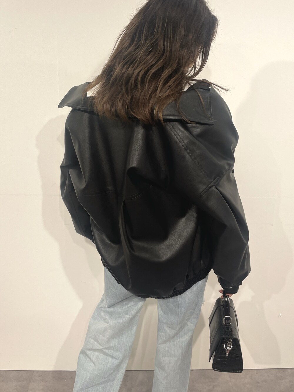 ブルー系のデニムパンツ、ブラック系のショルダーバッグ、ホワイト系のTシャツ/カットソーを着用したレディースの秋コーディネートの4枚目の写真