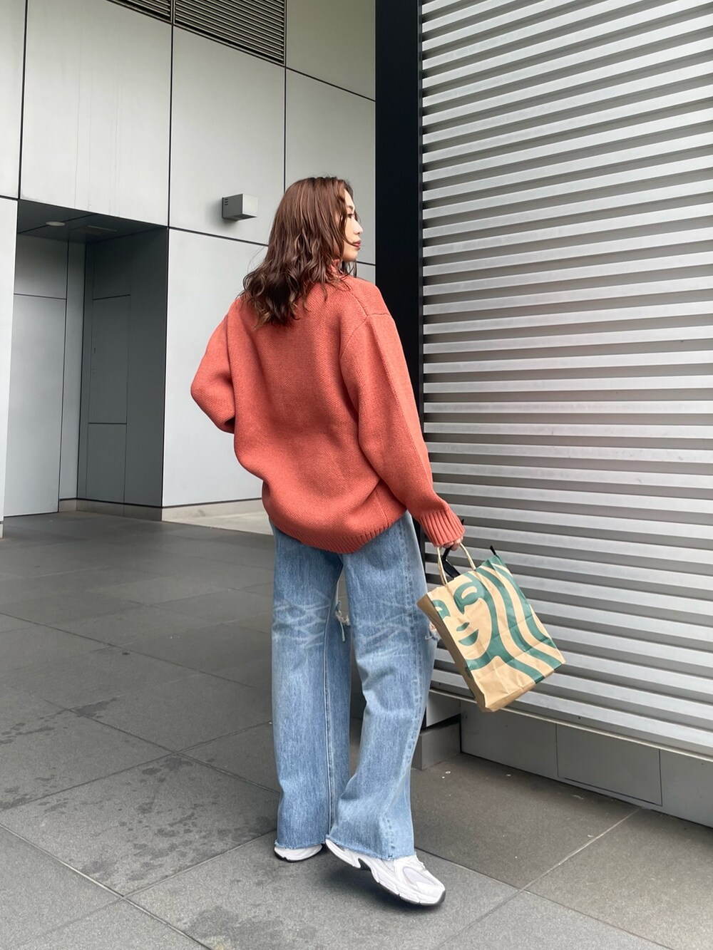 オレンジ系のニット/セーター、ブルー系のデニムパンツを着用したレディースの夏コーディネートの7枚目の写真