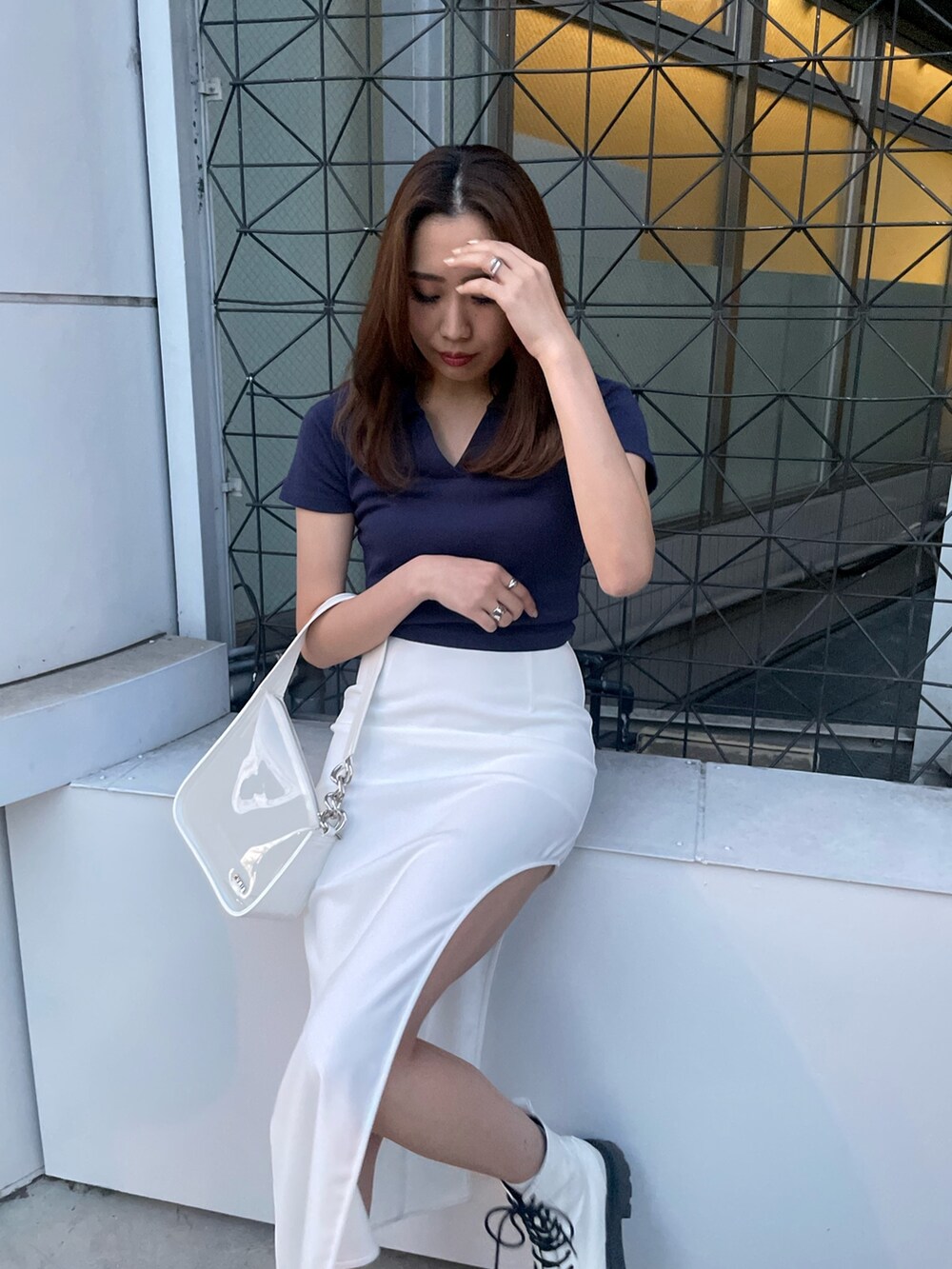 ホワイト系のブーツ、ホワイト系のスカート、ホワイト系のハンドバッグを着用したレディースの春コーディネートの2枚目の写真