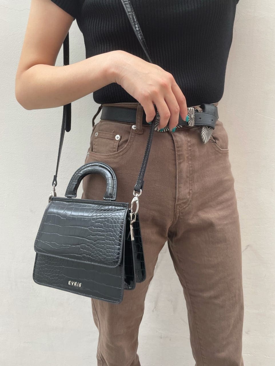 ブラウン系のデニムパンツ、ブラック系のサンダル、ブラック系のニット/セーターを着用したレディースの秋コーディネートの4枚目の写真