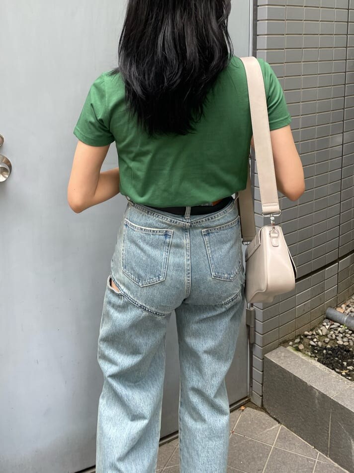 グリーン系のTシャツ/カットソー、ホワイト系のショルダーバッグ、ブルー系のデニムパンツを着用したレディースの春コーディネートの5枚目の写真