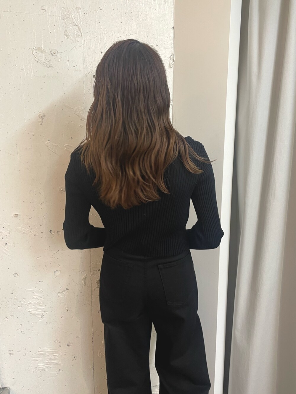 ブラック系のニット/セーター、ブラック系のショルダーバッグ、ホワイト系のブーツを着用したレディースの秋コーディネートの4枚目の写真