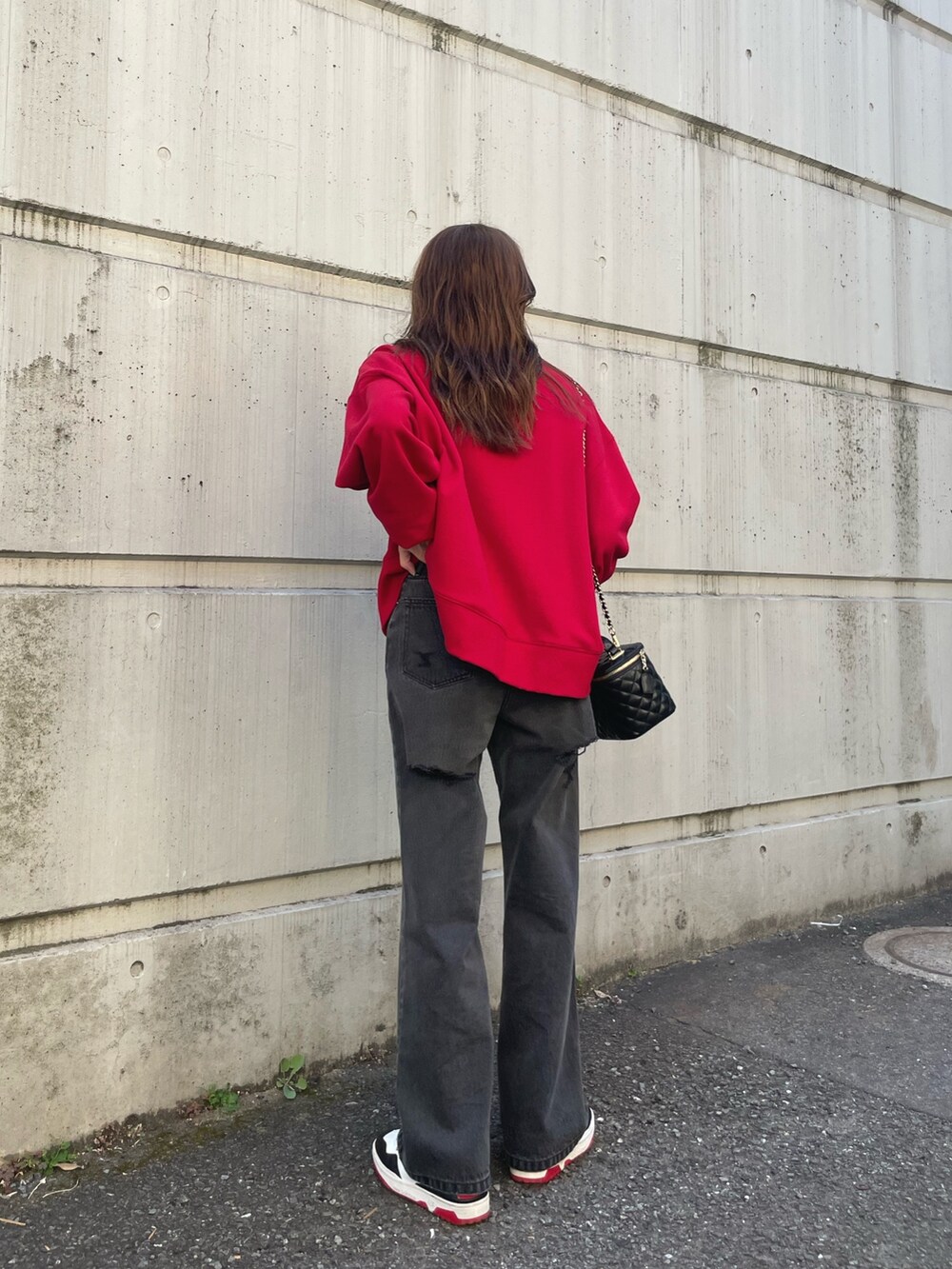 レッド系のスウェット、ブラック系のデニムパンツを着用したレディースの夏コーディネートの7枚目の写真