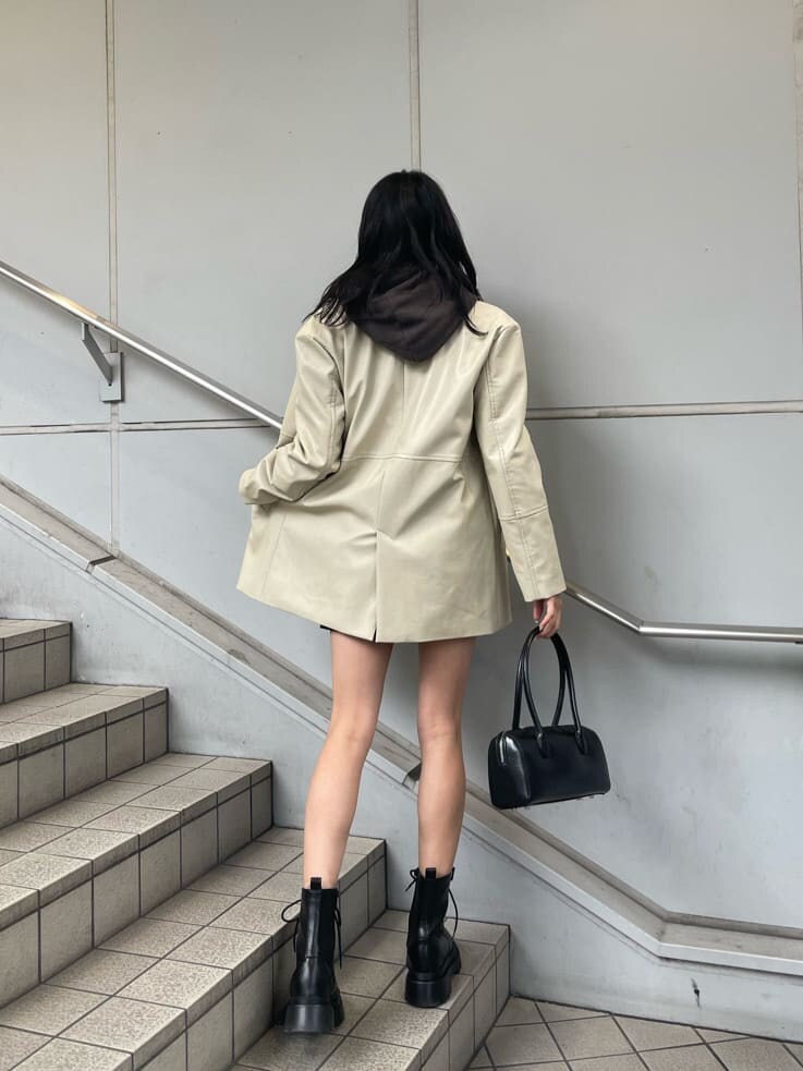 ホワイト系のテーラードジャケット、ブラック系のスカート、ブラック系のブーツを着用したレディースの冬コーディネートの2枚目の写真