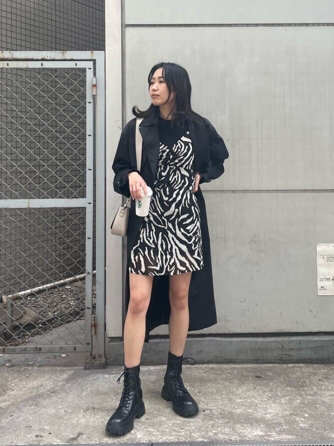 ブラック系のブーツ、ブラック系のトレンチコート、ブラック系のワンピースを着用したレディースの春コーディネートの3枚目の写真