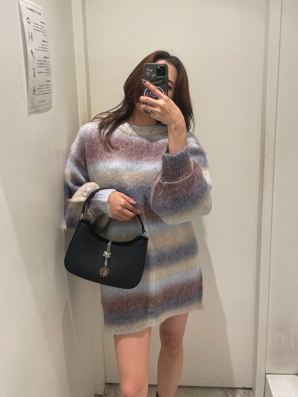 パープル系のニット/セーター、ブラック系のハンドバッグ、ブラック系のブーツを着用したレディースの秋コーディネートの2枚目の写真