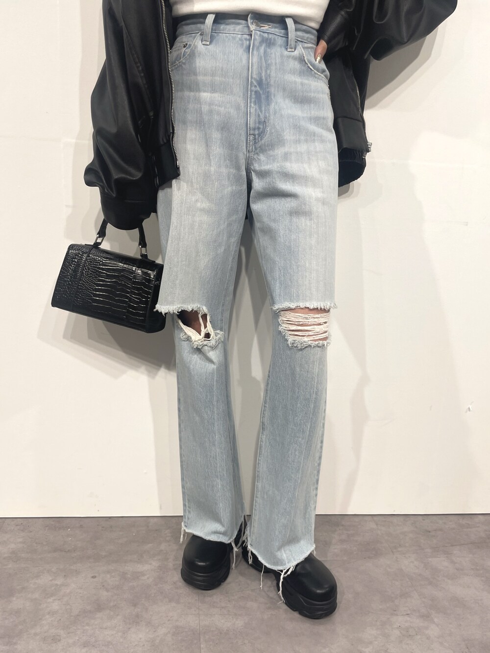 ブルー系のデニムパンツ、ブラック系のショルダーバッグ、ホワイト系のTシャツ/カットソーを着用したレディースの秋コーディネートの6枚目の写真