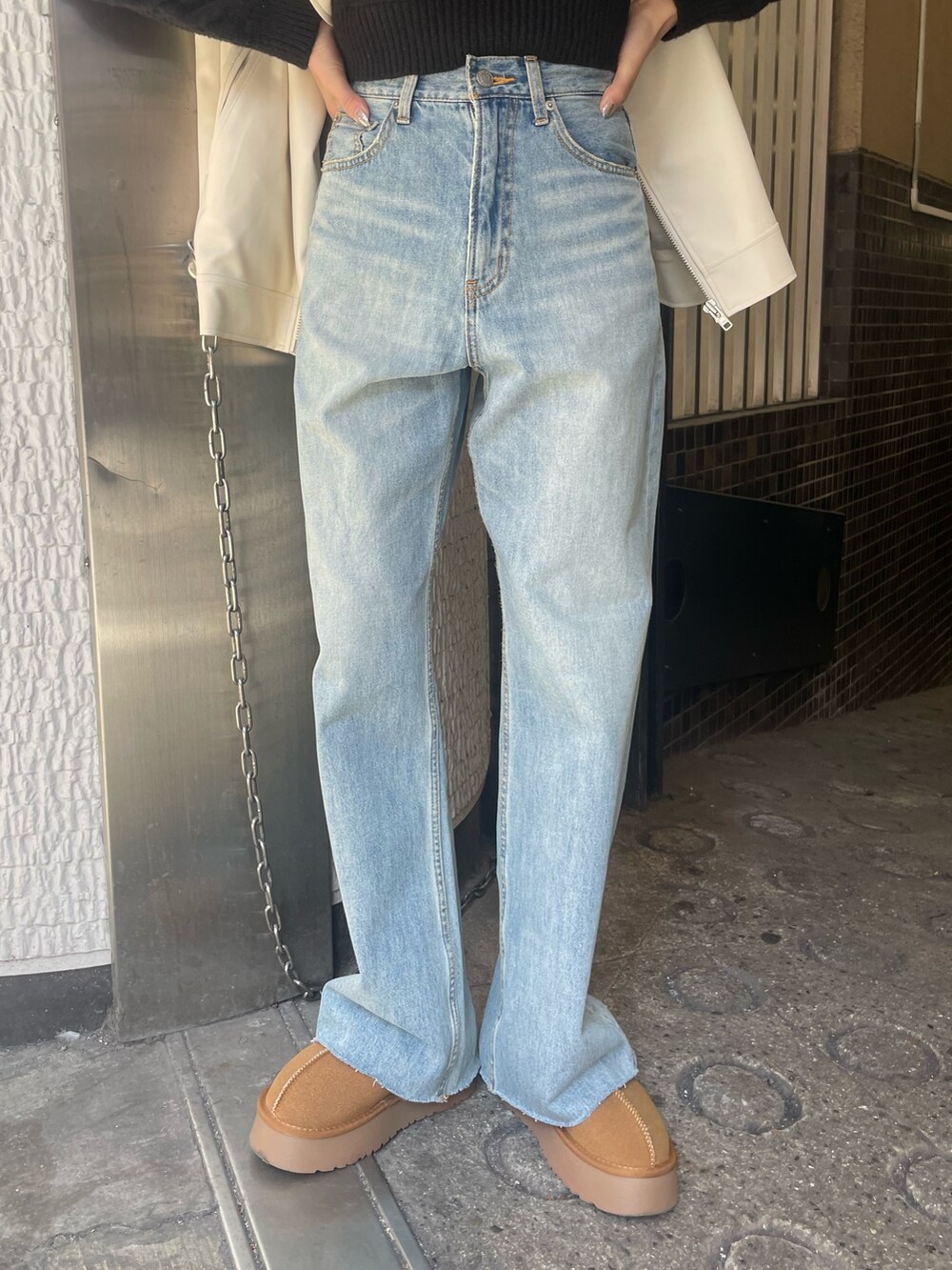 ブルー系のデニムパンツ、ブラック系のニット/セーター、ホワイト系のライダースジャケットを着用したレディースの冬コーディネートの8枚目の写真