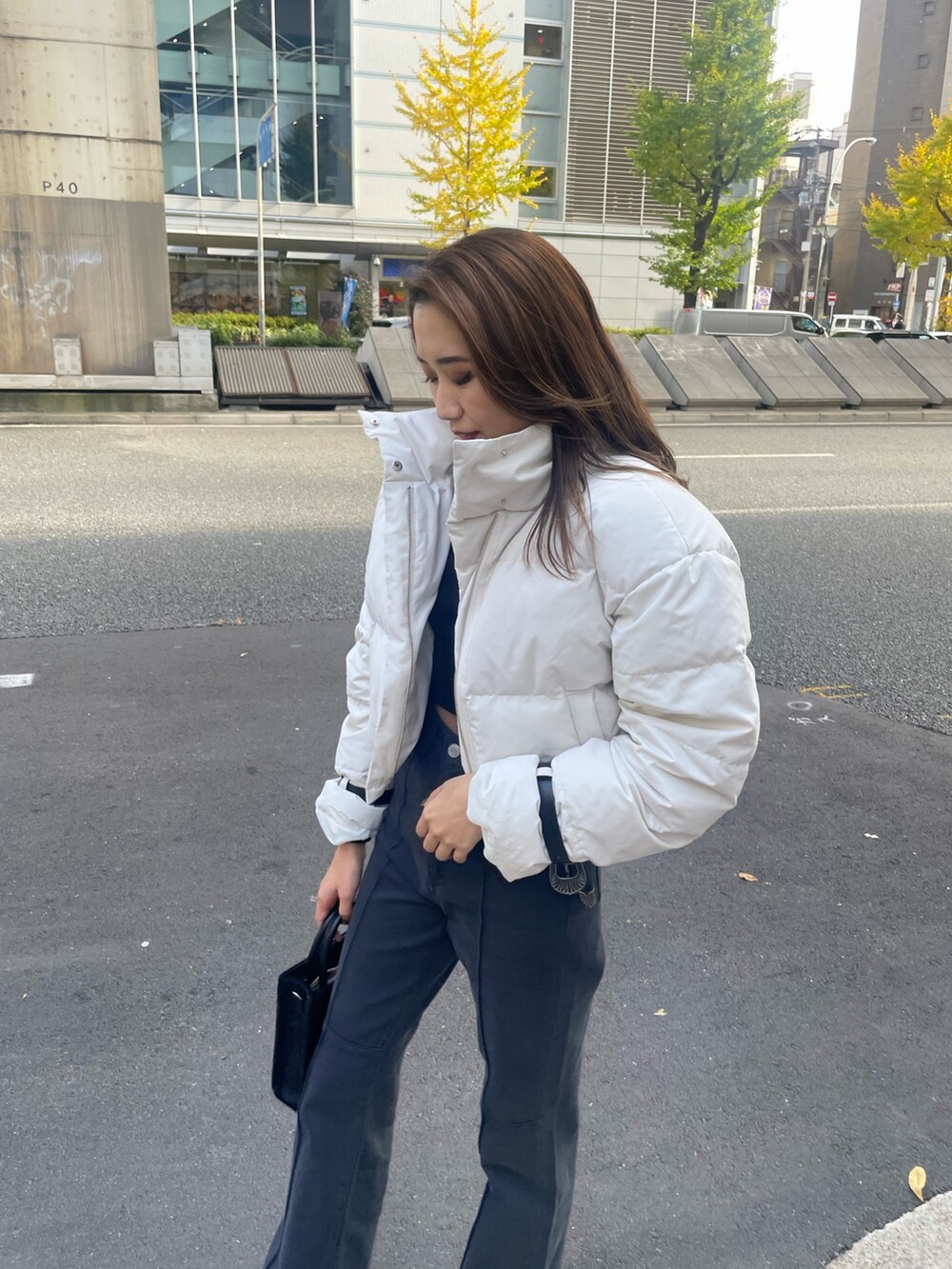 ホワイト系のダウンジャケット/コート、ブラック系のTシャツ/カットソー、ブラック系のショルダーバッグを着用したレディースの秋コーディネートの4枚目の写真