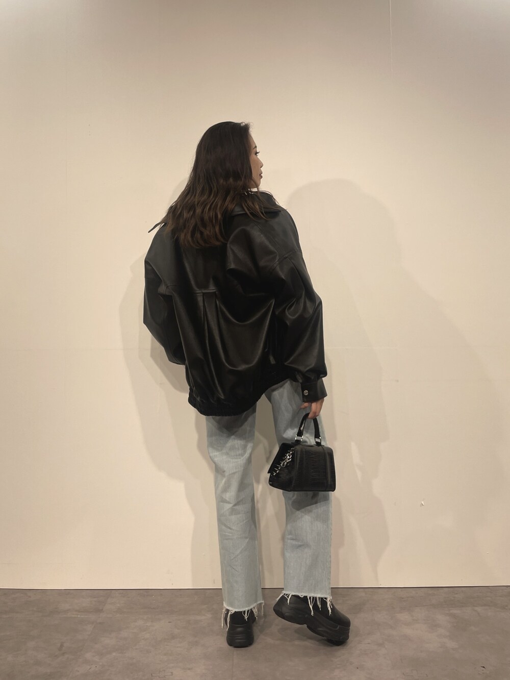 ブルー系のデニムパンツ、ブラック系のショルダーバッグ、ホワイト系のTシャツ/カットソーを着用したレディースの秋コーディネートの2枚目の写真