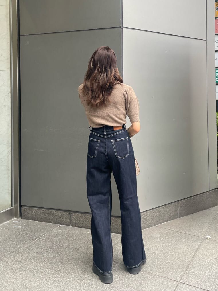 ブラック系のブーツ、ブラウン系のボストンバッグ、ブルー系のデニムパンツを着用したレディースの夏コーディネートの2枚目の写真