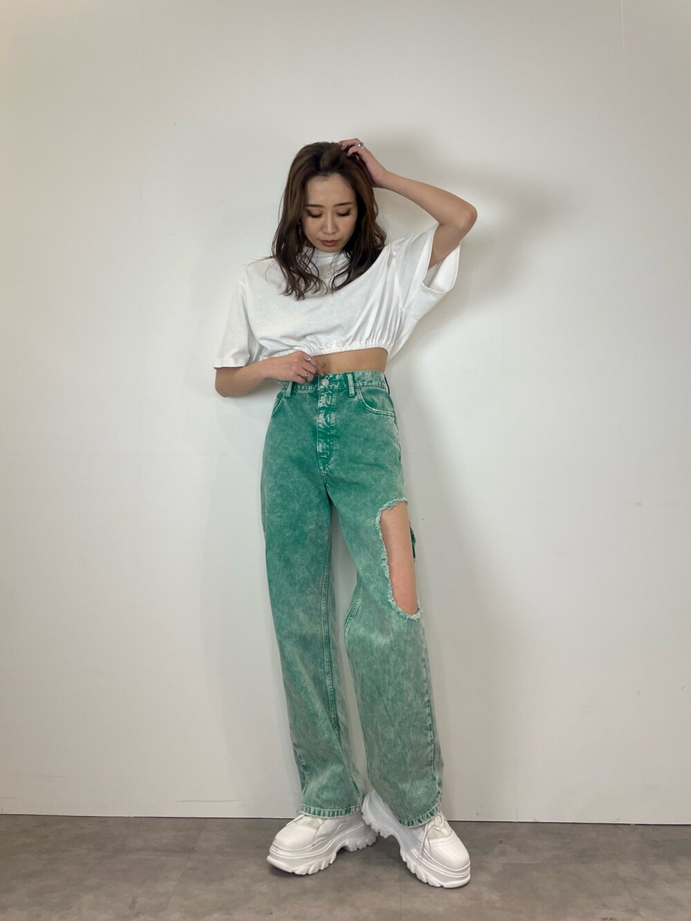 グリーン系のデニムパンツ、ホワイト系のスニーカー、ホワイト系のTシャツ/カットソーを着用したレディースの春コーディネートの2枚目の写真