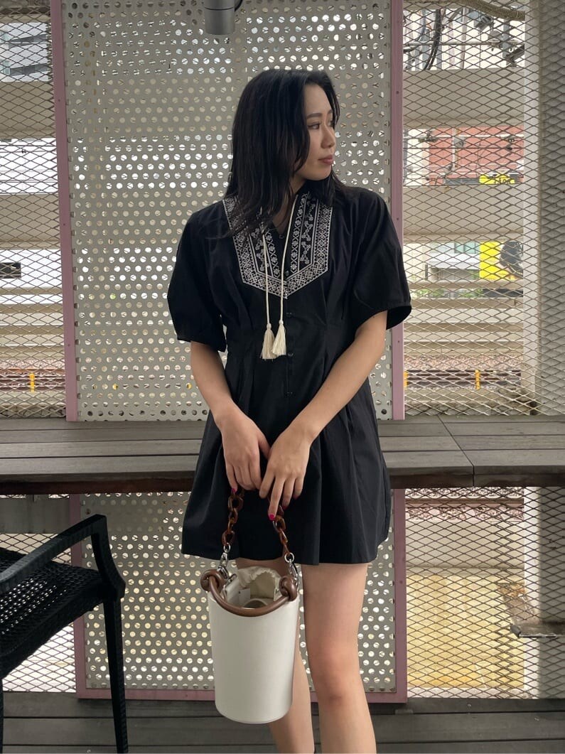 ブラック系のブーツ、ブラック系のワンピース、ホワイト系のショルダーバッグを着用したレディースの春コーディネートの4枚目の写真