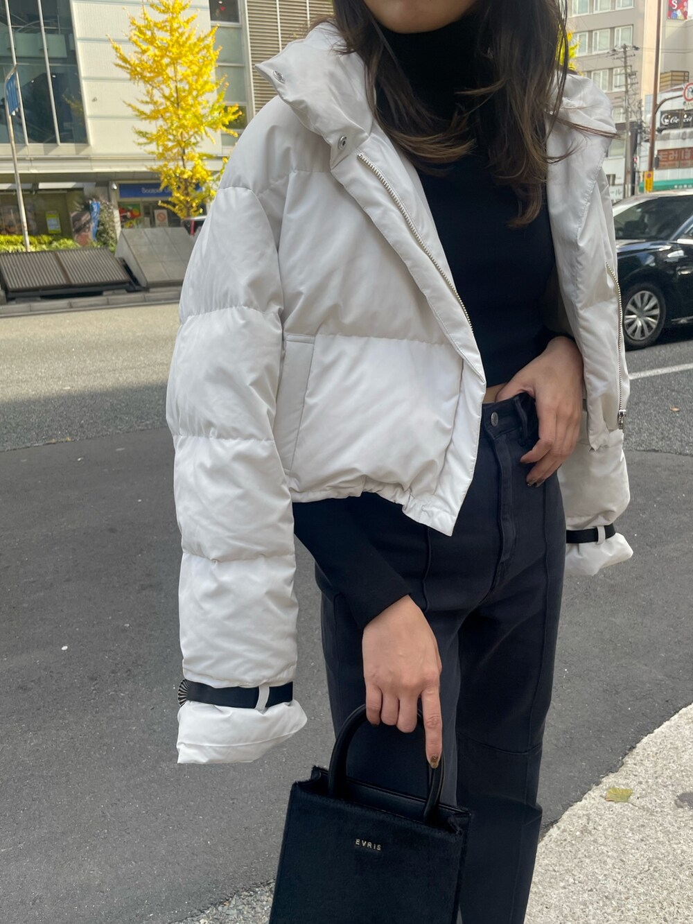 ホワイト系のダウンジャケット/コート、ブラック系のTシャツ/カットソー、ブラック系のショルダーバッグを着用したレディースの秋コーディネートの6枚目の写真