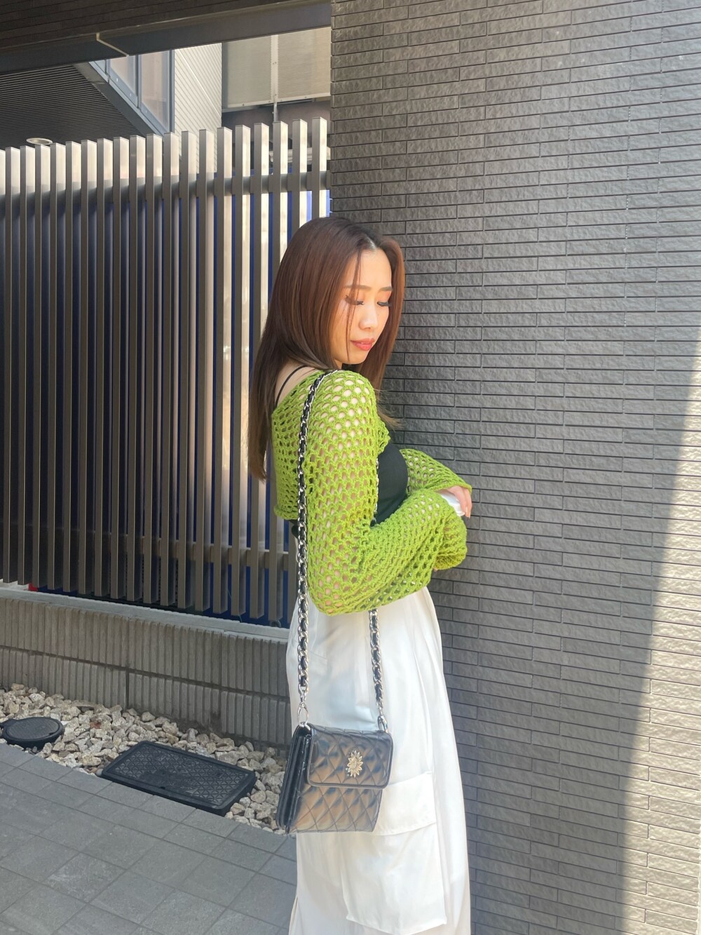 グリーン系のニット/セーター、ブラック系のニット/セーター、ホワイト系のスカートを着用したレディースの春コーディネートの4枚目の写真