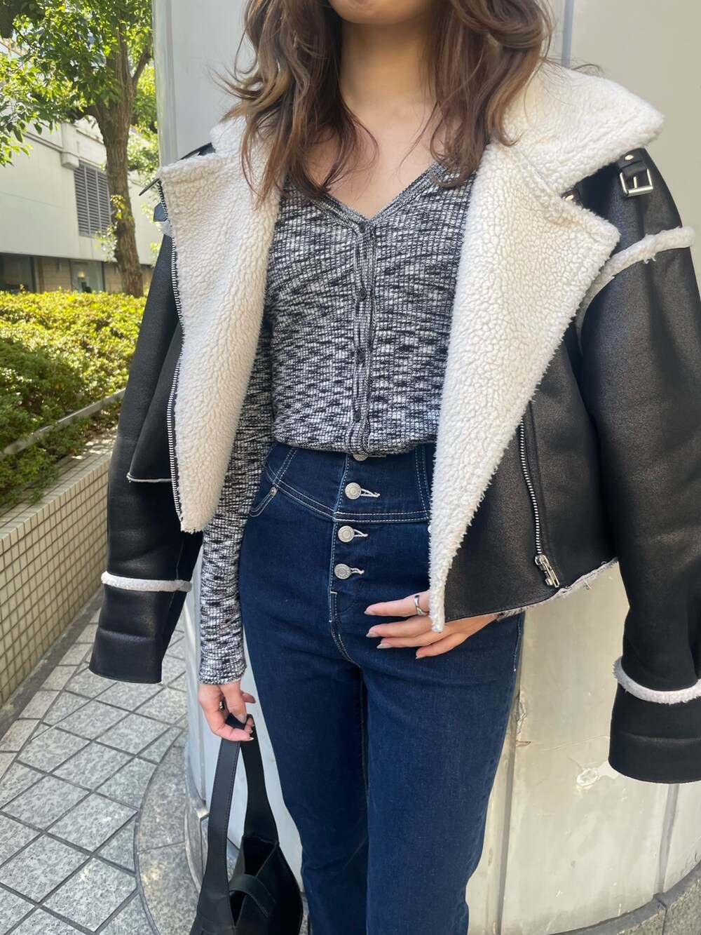 ブラック系のブルゾン、ブラック系のニット/セーター、ブルー系のデニムパンツを着用したレディースの冬コーディネートの9枚目の写真