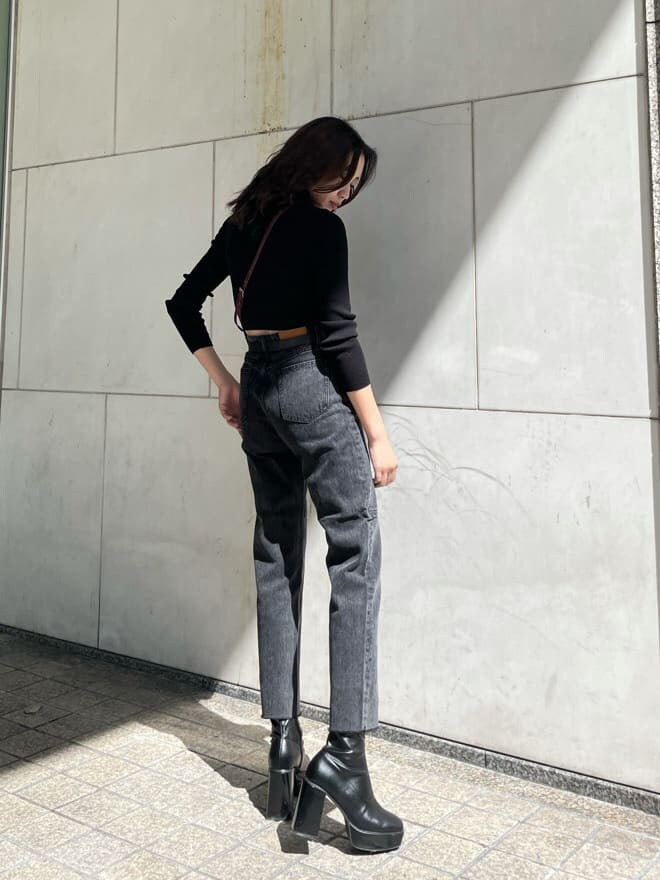 レッド系のショルダーバッグ、ブラック系のデニムパンツ、ブラック系のニット/セーターを着用したレディースの秋コーディネートの2枚目の写真