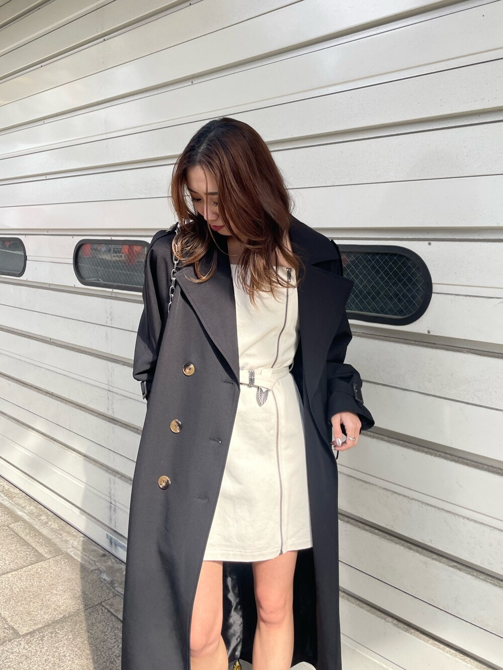 ブラック系のショルダーバッグ、ブラック系のトレンチコート、ホワイト系のワンピースを着用したレディースの冬コーディネートの5枚目の写真